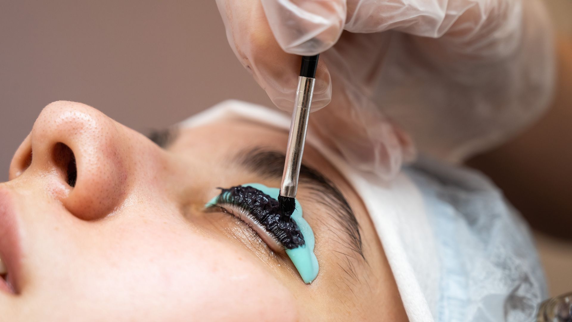 Eyelash extension procedure with black mascara and blue protective pad