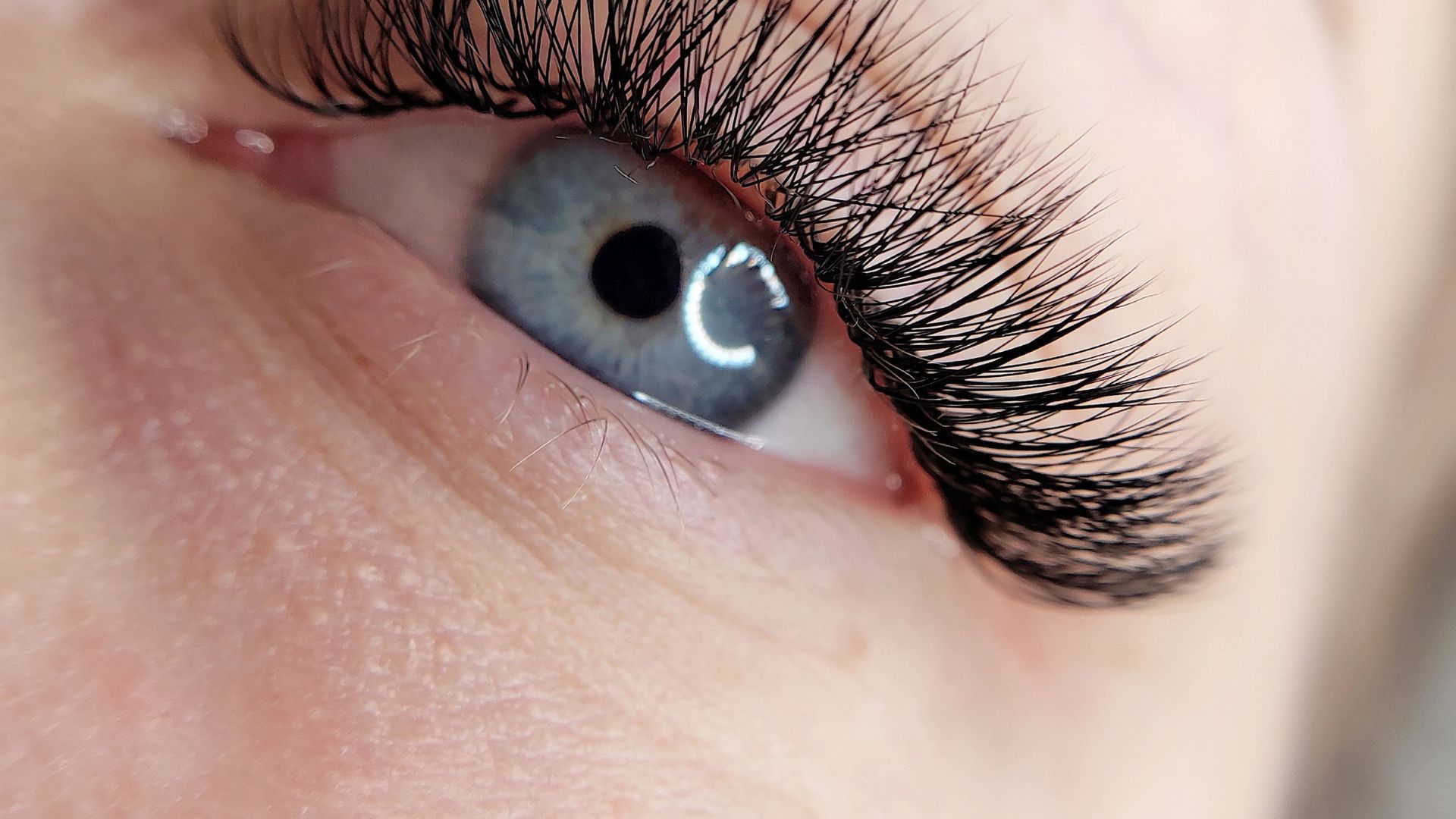 Close-up of blue eye with long eyelashes and light reflection