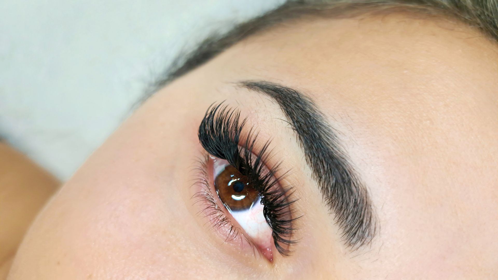 Close-up of a brown eye with long, dark eyelashes and defined eyebrow